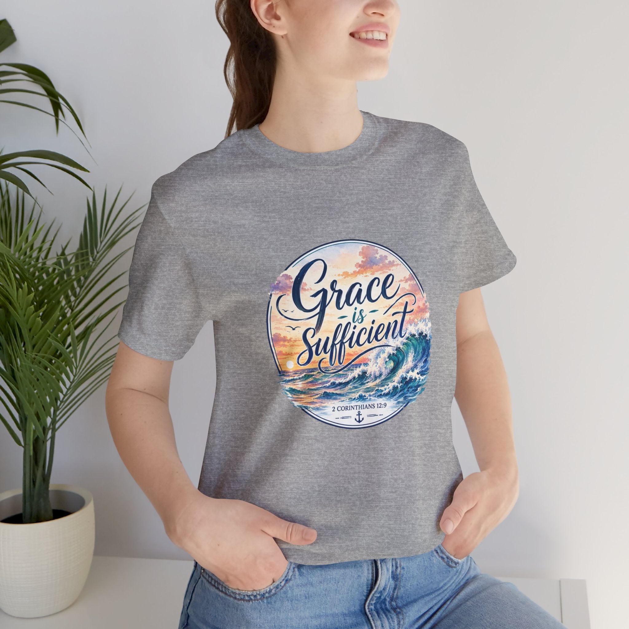 Grace Is Sufficient Tee displayed by a model, featuring a seaside design with calming colors and inspirational text.