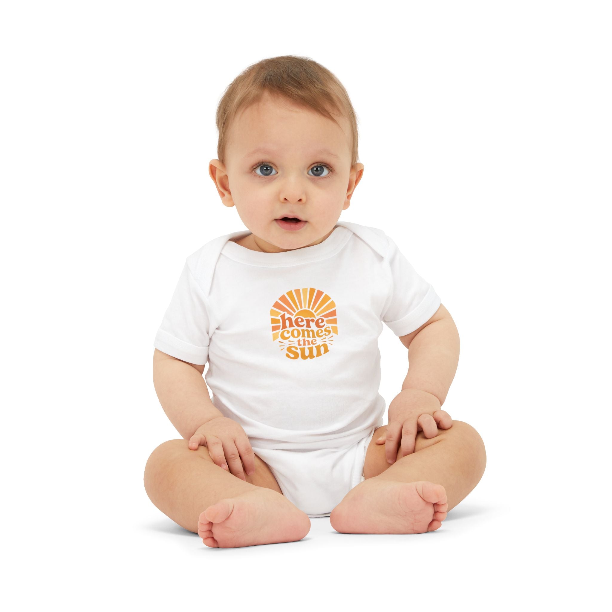 Cute Baby Bodysuit featuring the phrase 'Here Comes The Sun' on an infant sitting against a white background.