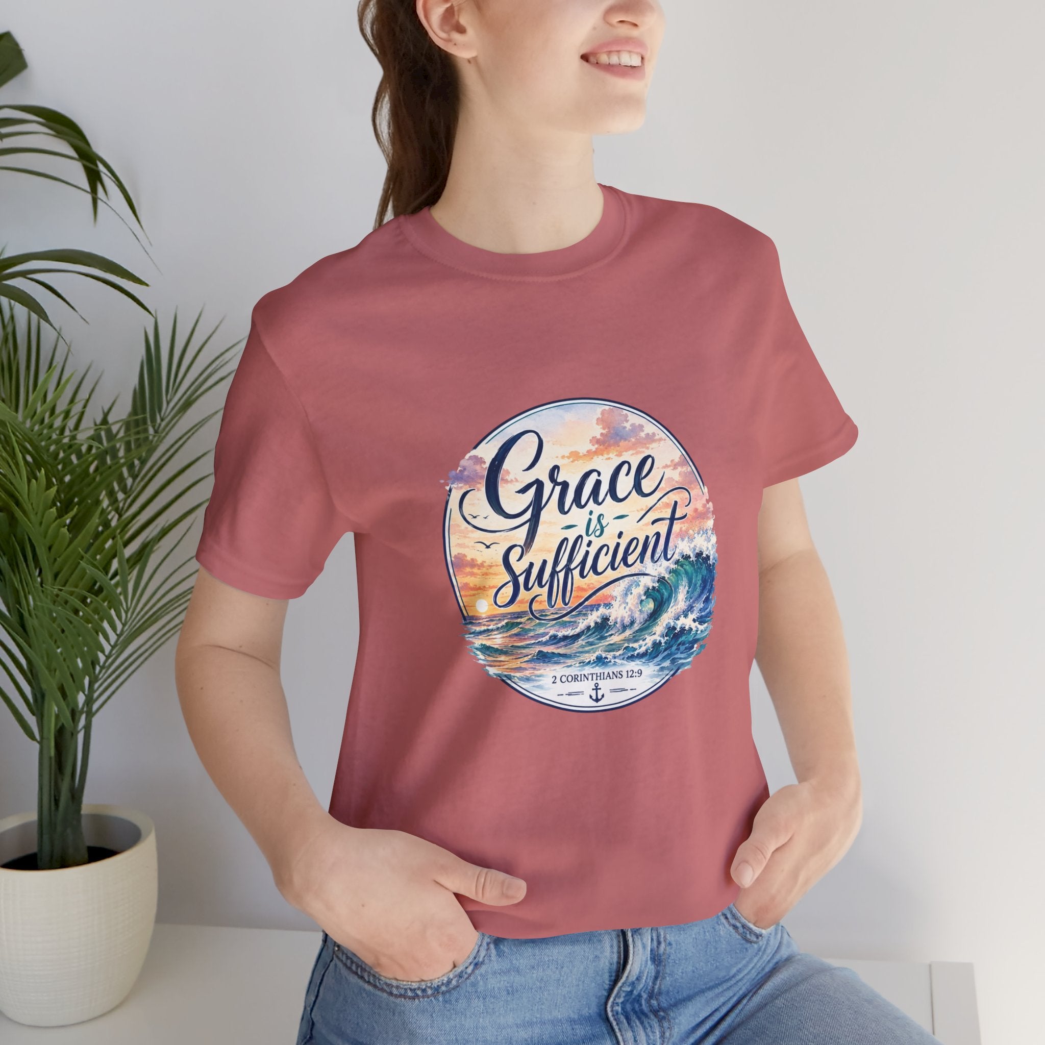 Grace Is Sufficient Tee worn by a woman, featuring a seaside graphic, soft cotton fabric, and inspirational message.