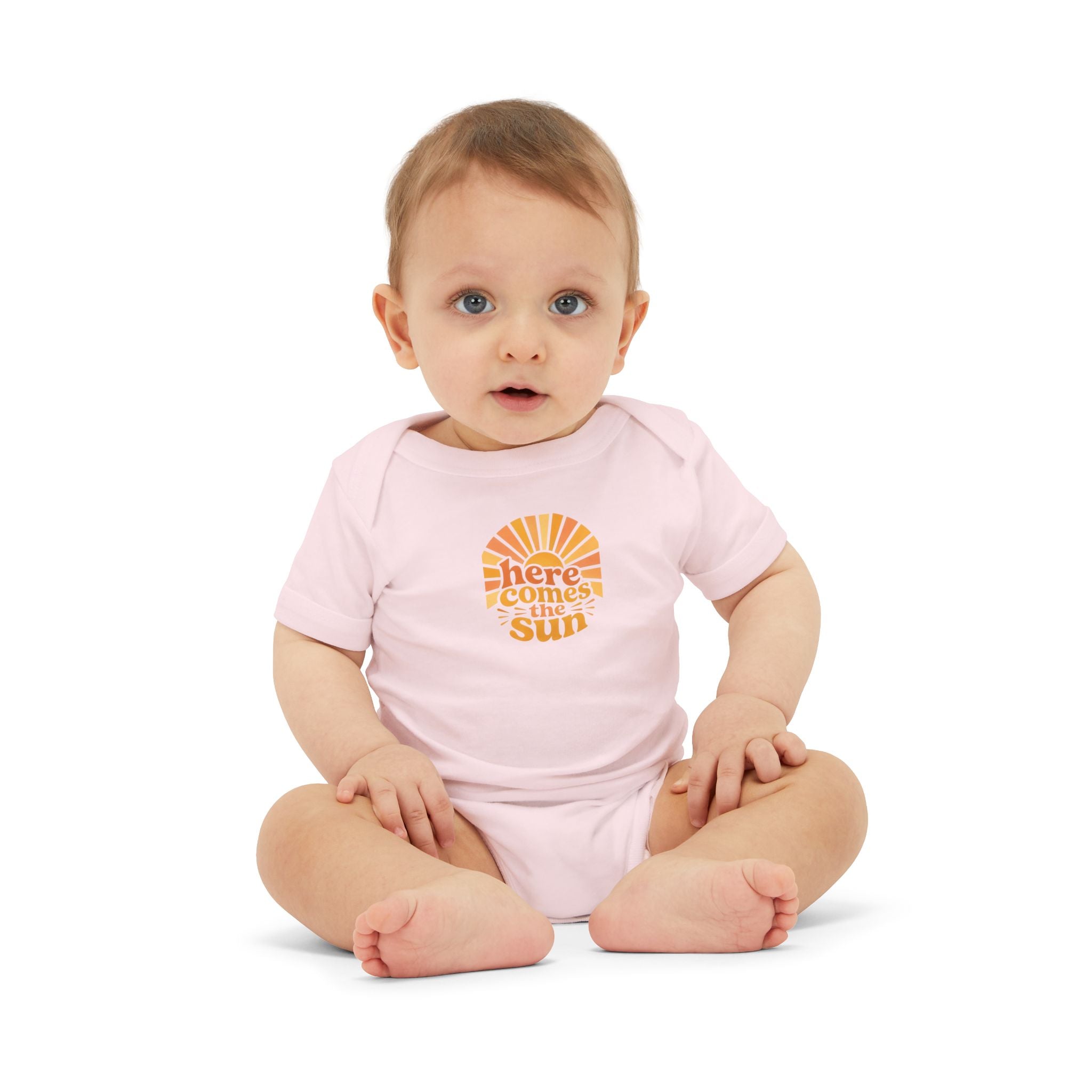 Cute Baby Bodysuit in pink with 'Here Comes The Sun' graphic, worn by a seated baby.