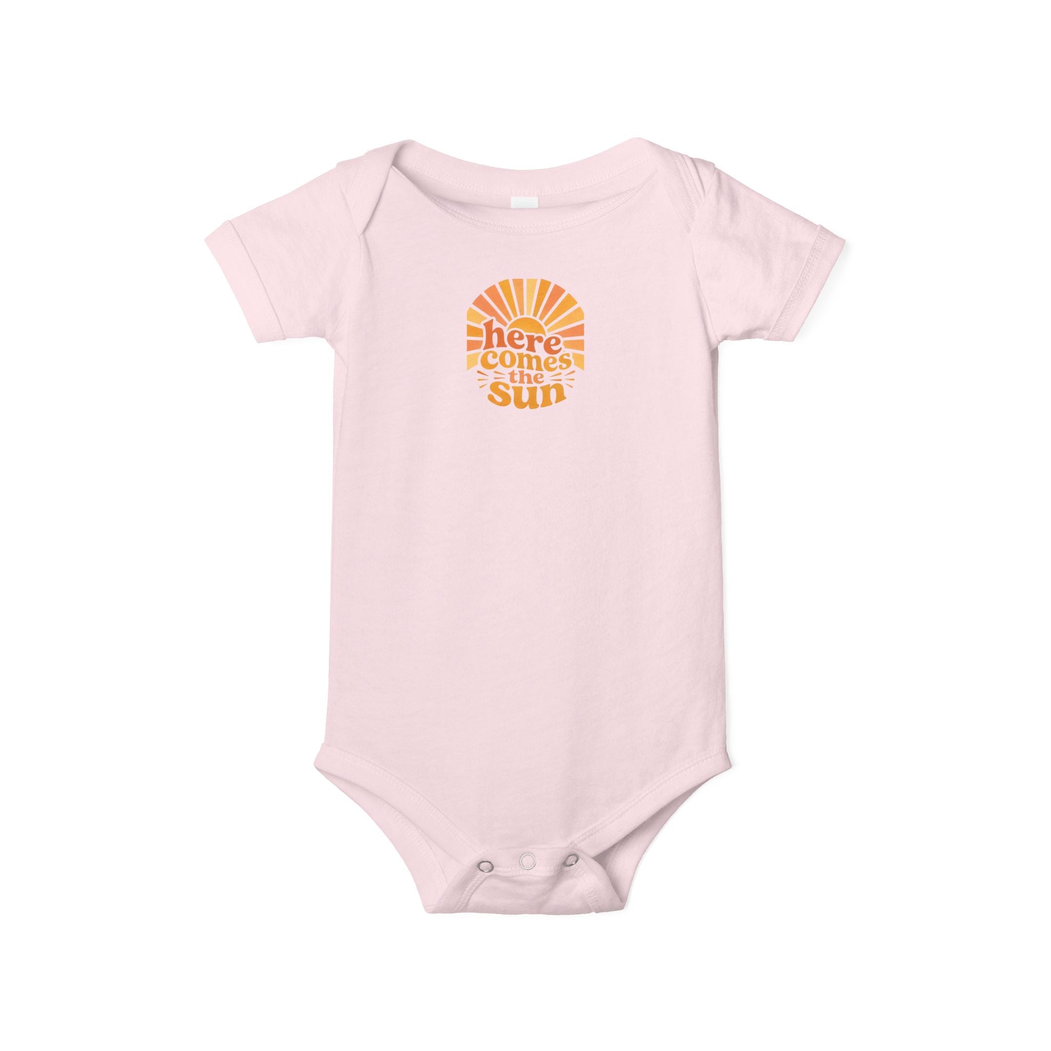 Cute Baby Bodysuit with cheerful sun design and uplifting phrase 'Here Comes The Sun' in orange on a pink background.
